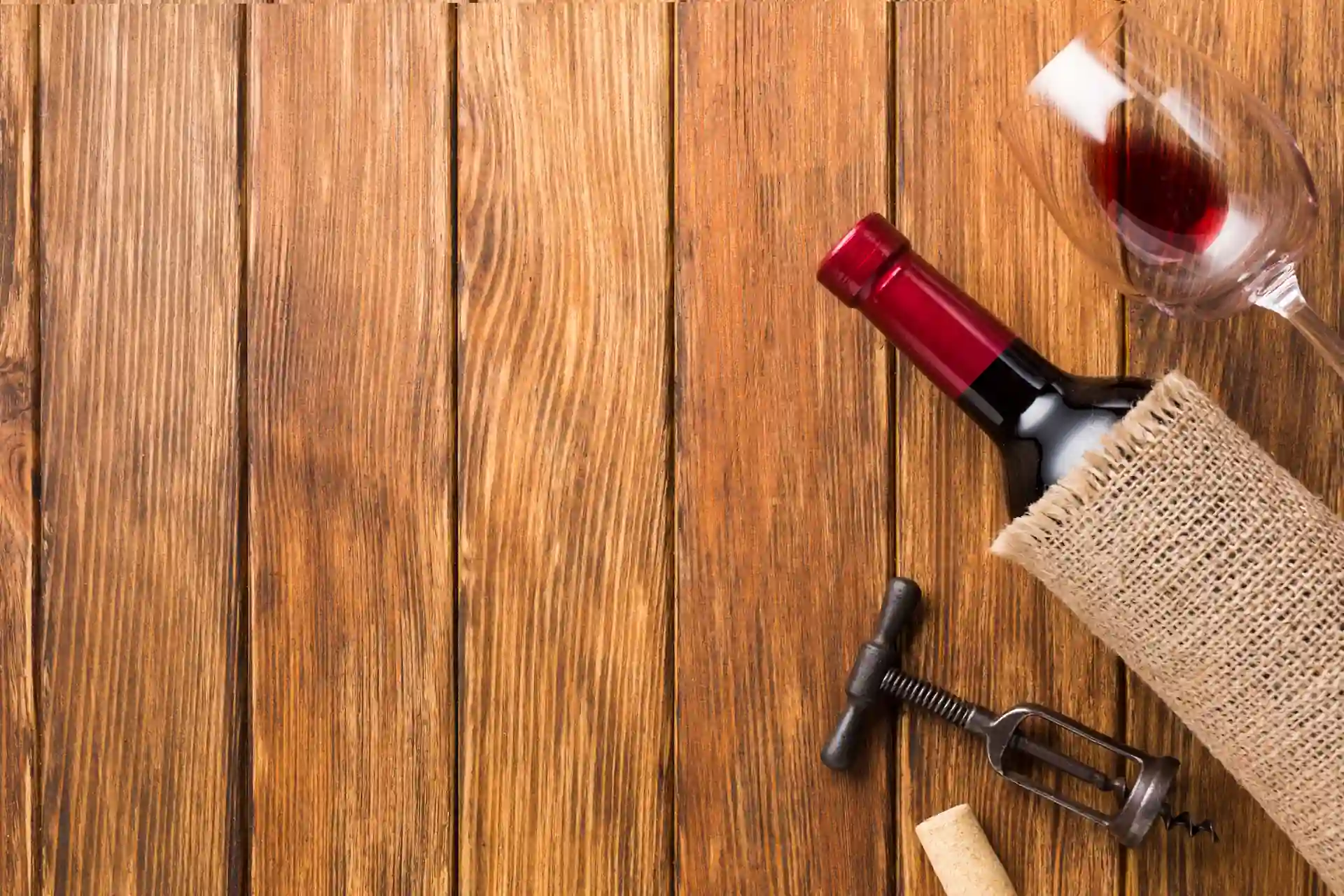 Botella y copa de vino tinto sobre mesa de madera